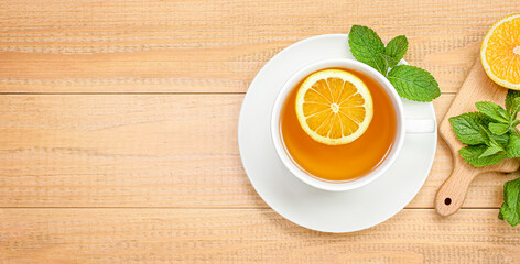 mug of tea with mint and lemon on a wooden background. view from above