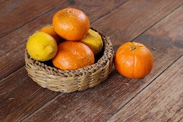group of red oranges and yellow lemons. Healthy products placed in a wicker basket on a rustic...