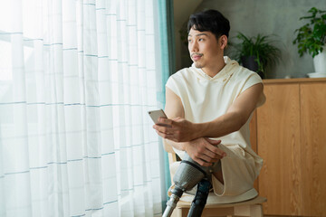 Fototapeta premium 窓際でスマートフォンを見る男性