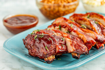 Sliced barbeque ribs on blue plate with side dishes