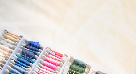 Closeup image of the colorful thread yarn swatch with the plastic box and put on the white cotton background,