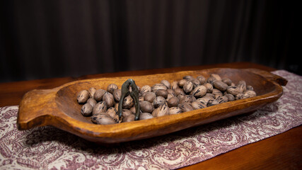 Raw in shell whole Pecan nuts in a wooden bowl on a wood table with a vintage nut cracker