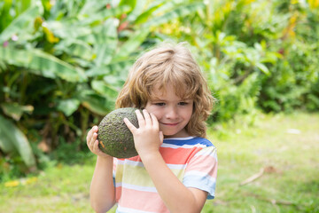 Kid eating and enjoying an avocado on a nature background. Healthy food for kids concept.