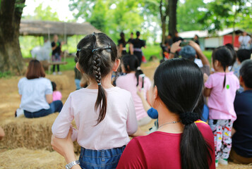 Rear view of mother and daughter watching the culture show in the nature park.