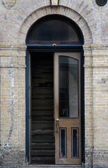 old open door and stairs of yellow brick building door