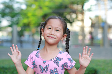 Asian child or kid girl smile and show up her hands in the garden outdoor.