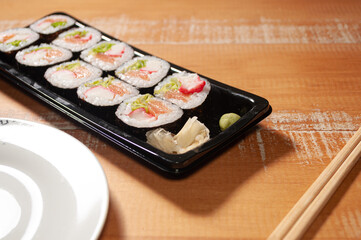 A sushi bar with portion of slices of ginger and wasabi, a pair of chopsticks and a white plate
