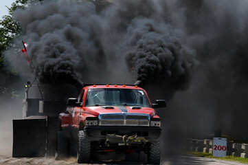 red truck with lots of black diesel smoke at a tractor pull - obrazy, fototapety, plakaty