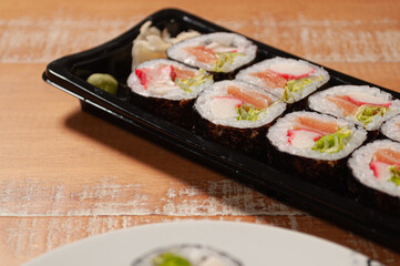 A sushi bar with portion of slices of ginger and wasabi, a pair of chopsticks and a white plate