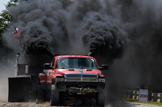 red truck with lots of black diesel smoke at a tractor pull