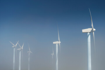 several wind turbines on a wind farm above the clouds