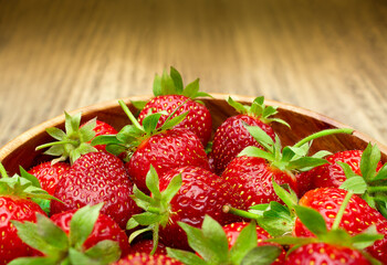 Fresh strawberries in a bowl on a wooden table. Summer food, fruit background, delicious food. Side view, copy space.