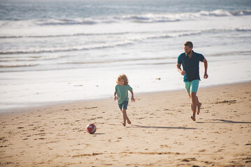 Father and son play soccer or football on the beach. Daddy with kid boy playing on a summer day.