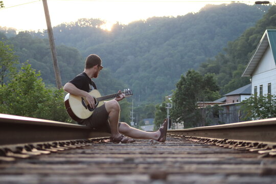 Man playing guitar on the train tracks 