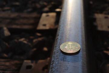 BItcoin token on the train tracks with a sunset in the background