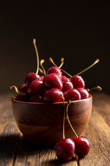 Cherries on wooden table with water drops on the bowl