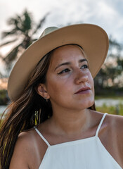 young hispanic woman in hat with her tired look looking to the side on a beach - latinx