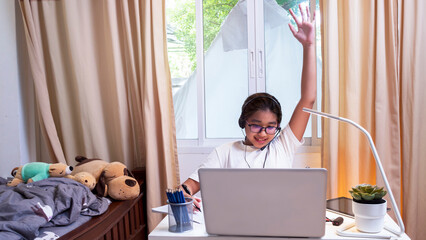 Asian girl in headphones sit at desk study online on laptop. Kid wear headset learning using internet lessons on quarantine. Student learning virtual internet online class from school due to covid-19