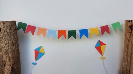 Cheerful and colorful June party decoration with flags and kites fixed on wood, wooden background. Brazilian june party. Space for text.