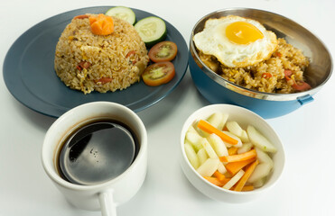 Fried rice served with fresh tomatoes and meatballs in a green tosca ceramic plate and pickles on a white bowl on a white background