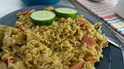 Fried rice served with fresh tomatoes and meatballs in a green tosca ceramic plate and pickles on a white bowl on a white background