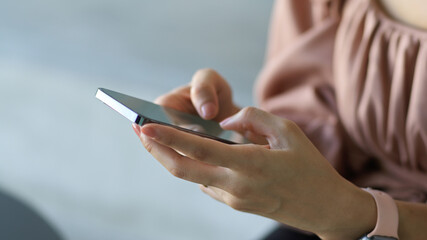 Close up view of female office hands texting message on smartphone in office room