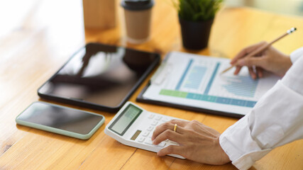 Side view of businessperson hands working with calculator and paperwork on office desk