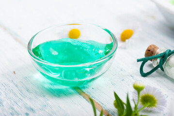 beauty product samples with chamomile flowers on white wooden table