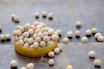 closeup bunch the ripe yellow brown peas beans in the plastic bowl over out of focus wooden brown background.