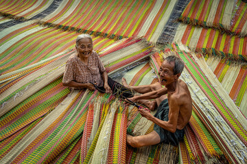 Top view of old Vietnamese lover craftsman making the traditional vietnam mats with happiness...