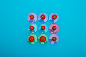 Red ripe tomatoes on colored coasters on a blue background