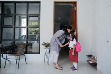 mother kissing her daughter forehead before taking her to school. asian pupil with uniform