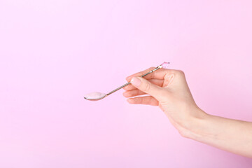 Female hand with spoon of tasty yogurt on color background