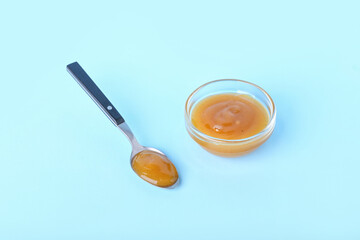 Bowl and spoon with tasty apricot jam on color background