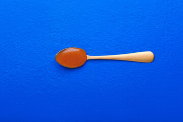 Spoon with tasty apricot jam on color background