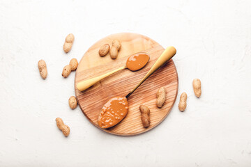 Fototapeta na wymiar Spoons with tasty peanut butter on light background