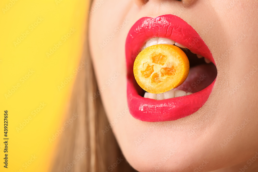 Wall mural Beautiful young woman with sweet cumquat, closeup