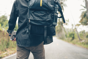 rear view of man with backpack hold passport and map hiking and walking on the road in forest. Backpack travel concept.