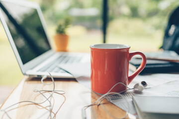 coffee cup and earphone and other travel accessories around on the table. Vocation, travel, holidays and backpack concept.