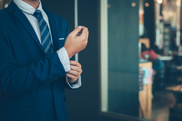 businessman wearing business suit fasten cufflink or button on sleeve of classic jacket and factory...