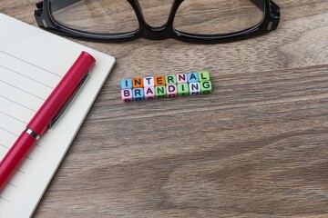 Internal branding from colorful cubes on the wooden table with eyeglasses, and pen on the notebook 