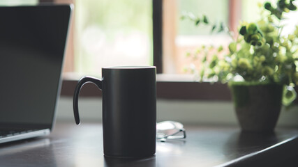 Workspace concept in dark tone color with laptop and cup of coffee on wooden table. Online working from a cafe, portable office concept.