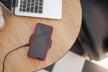 Charging mobile phone battery with wireless device in the table. Smartphone charging on a charging...