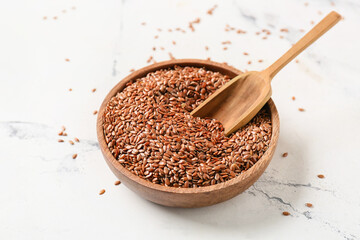 Bowl and scoop of flax seeds on white background