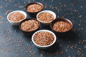Composition with bowls of flax seeds on dark background