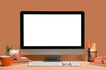 Stylish workplace with computer and orange accessories.