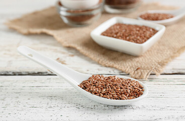 Spoon with flax seeds on white wooden background