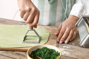 Female chef making delicious ravioli at table, closeup