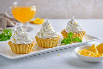 Tartlets with orange jam and protein cream decorated with orange zest on a white plate