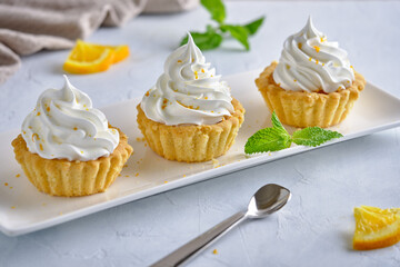 Tartlets with orange jam and protein cream decorated with orange zest on a white plate